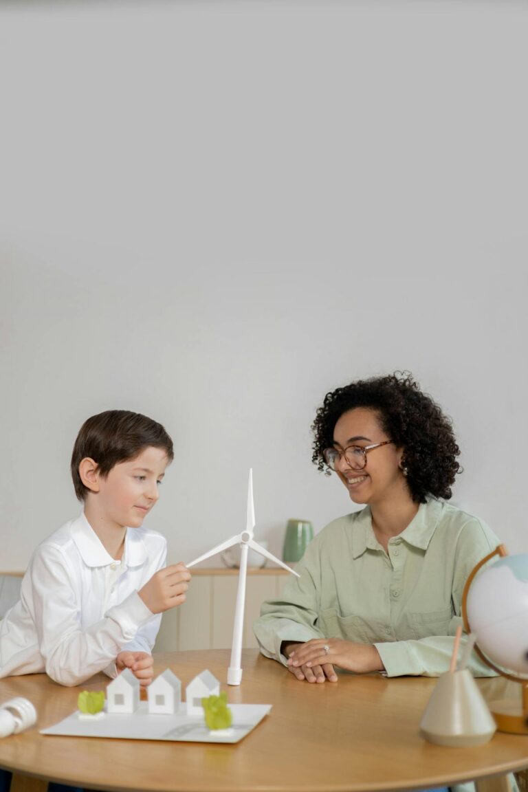 Child and teacher exploring wind energy with turbine model in classroom.