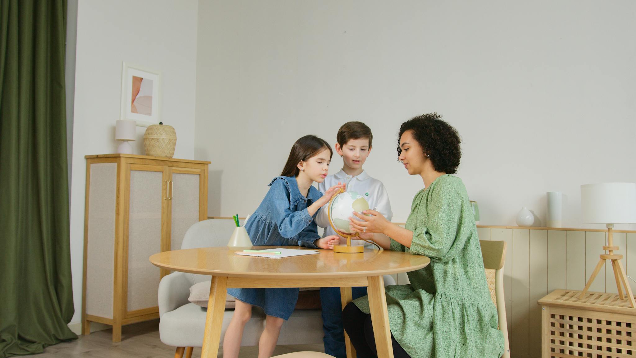 Two children and a teacher explore a globe together indoors, promoting education.