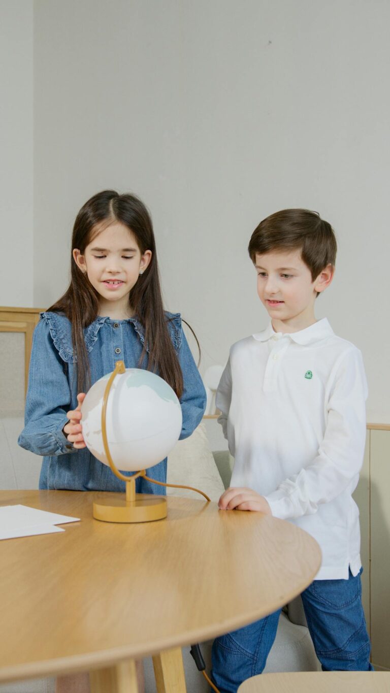 Two children engage with a globe, learning geography in a classroom.