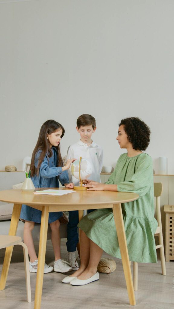 A teacher and two children engage in a hands-on science activity indoors.