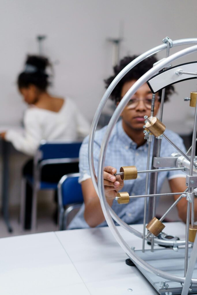 Diverse college students interacting with physics equipment in a science lab setting.